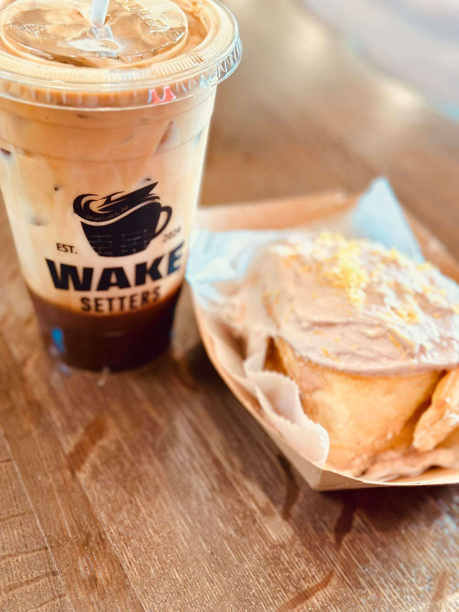 Wake Setters branded coffee cup with cinnamon roll